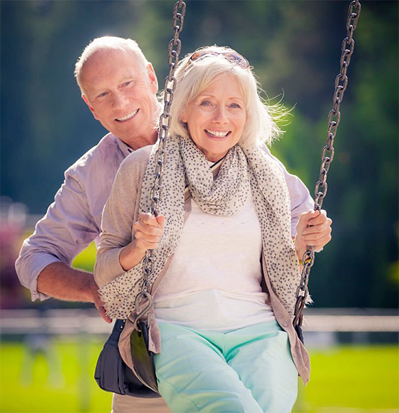 Senior couple enjoying playful moment on a swing, symbolizing engagement and joy in community life at The Residence at Gramercy.