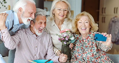 Seniors enjoying a joyful moment together, celebrating and taking a selfie, reflecting the community engagement and social activities at The Residence at Gramercy.